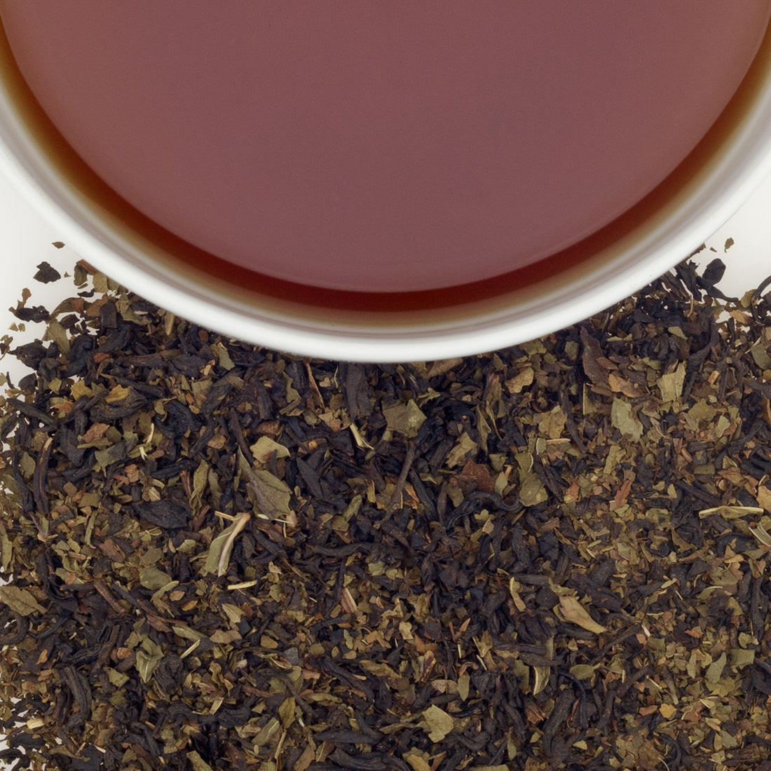 Close up of loose chocolate mint tea by harney and sons with a cup of brewed tea