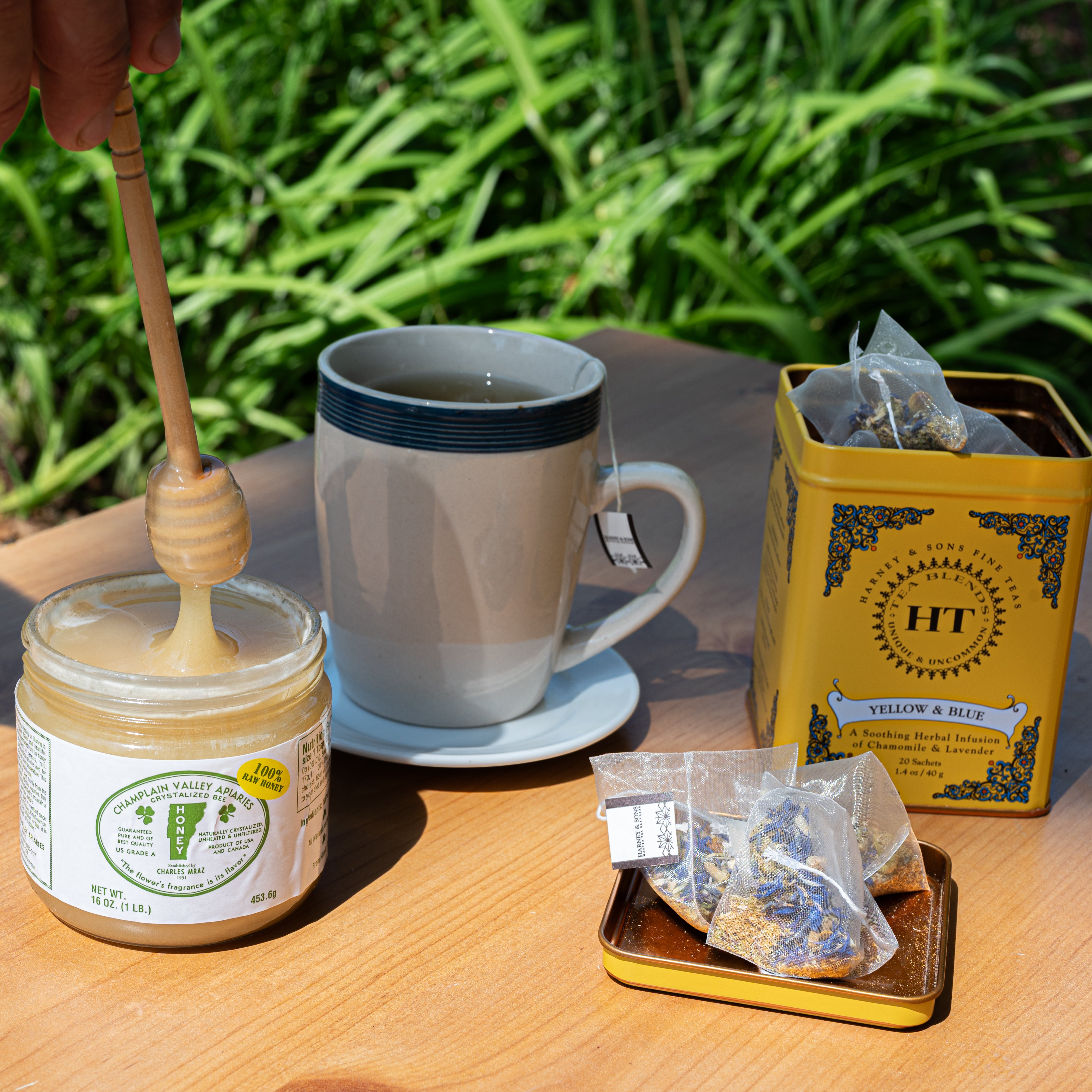 table with mug of brewed tea, honey, and open tin of harney and sons yellow and blue tea blend