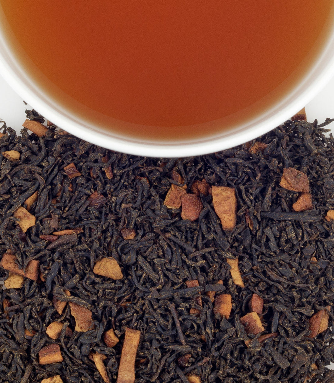 Close up of loose leaf Harney & Sons Hot Cinnamon Sunset tea with a cup of steeped tea