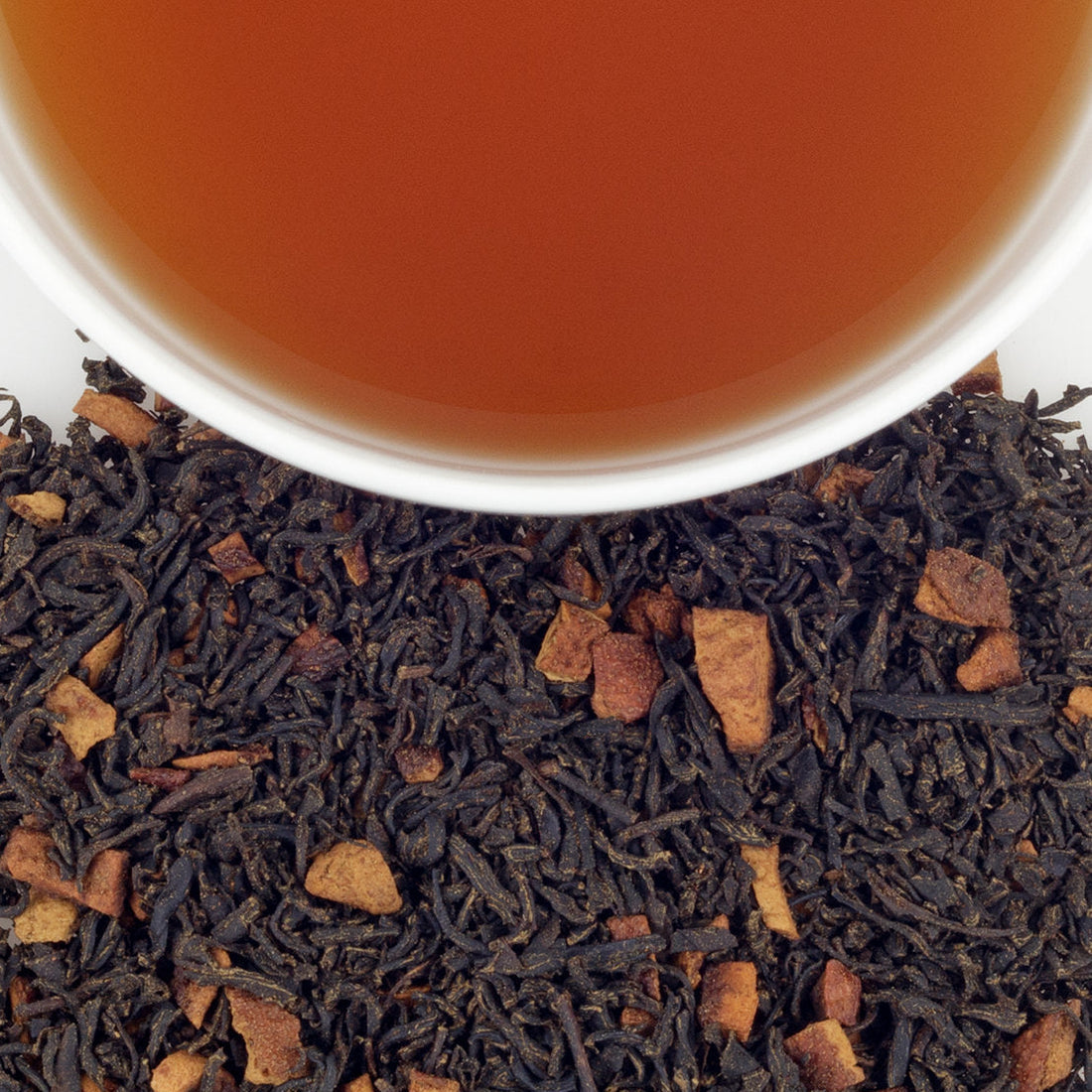 Close up of loose leaf Harney & Sons Hot Cinnamon Sunset tea with a cup of steeped tea